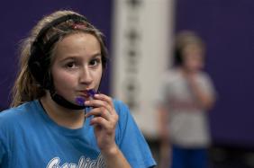 Erica Chapman, 11, readjusts her mouth piece after wrestling her partner Thursday at Bloomington South High School. Photo by Mark Felix.
